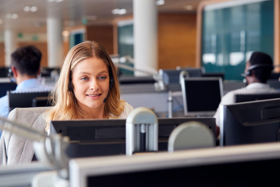 businesswoman wearing telephone headset talking to caller in customer services department.jpg